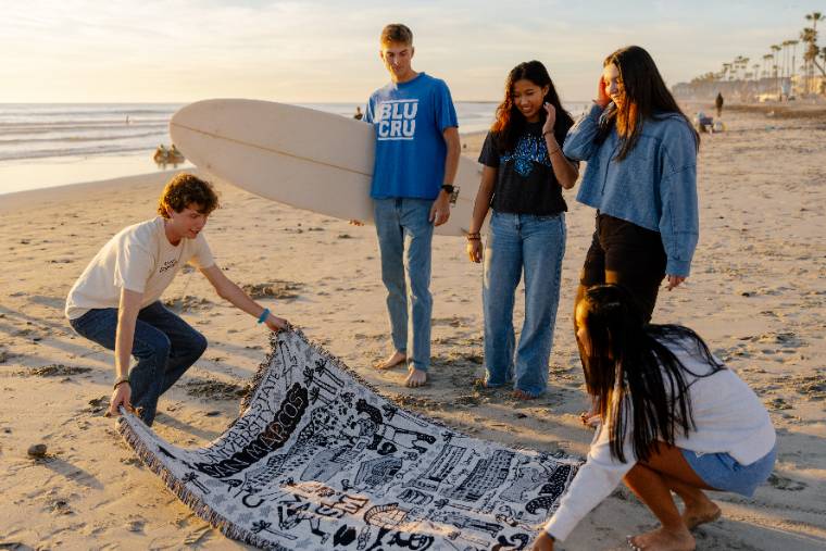 Students laying down a towel on the beach