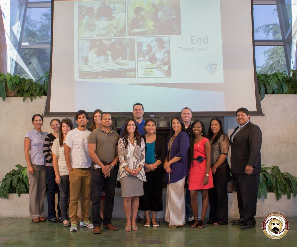 A group of program participants standing in front of a projector screen showing the end of a slideshow