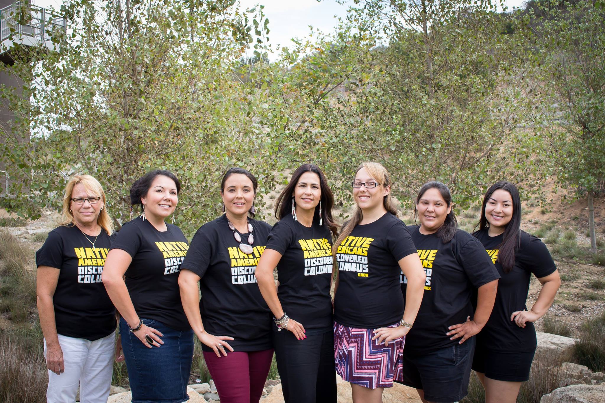 CICSC students and faculty standing together outside wearing black "Native Americans Discovered Columbus" shirts with the words "Native Americans" in yellow and the words "Discovered Columbus" in white