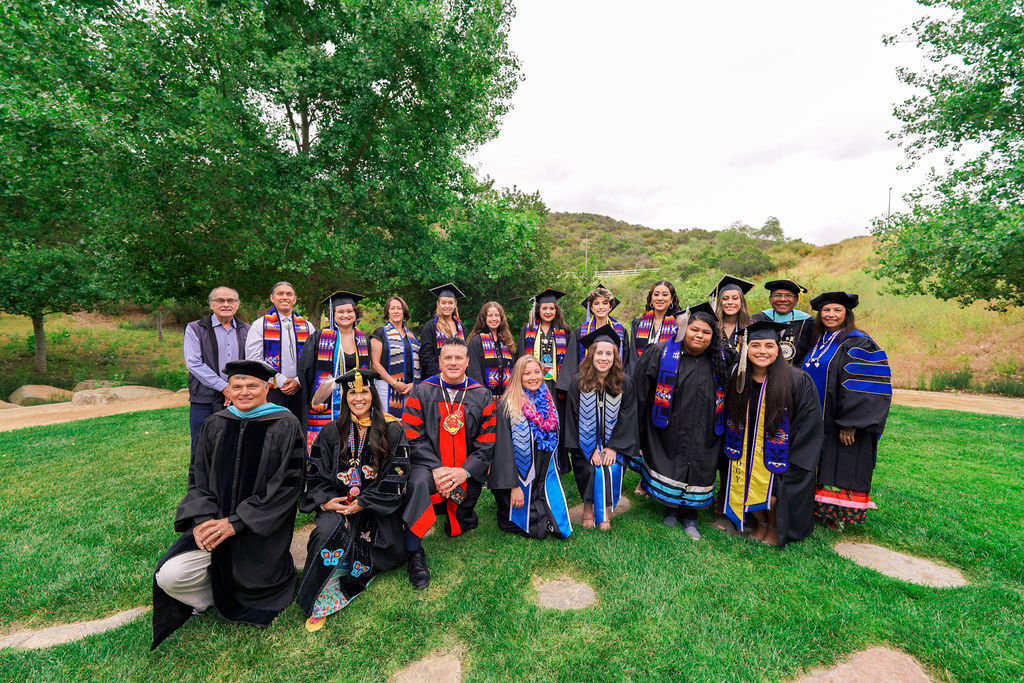 Group picture of 2022 American Indian graduates and faculty in their caps, gowns, and stoles