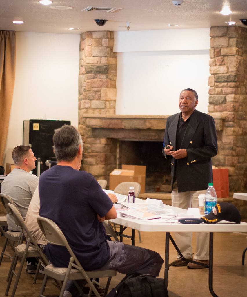 An instructor standing in front of a table of participants and speaking during a PL280 course.