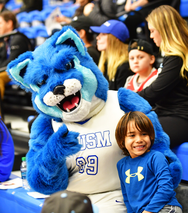 cougar mascot posed with a smiley little boy at a csusm game