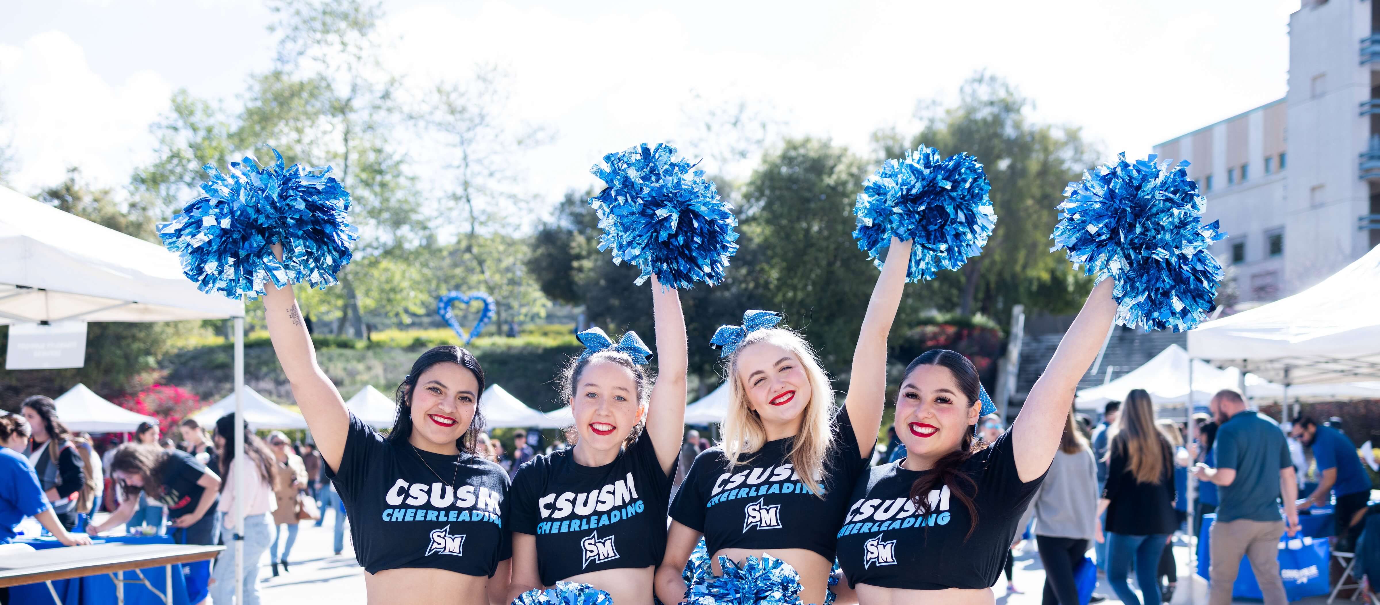 Four cheerleaders smiling at Cougar Blue Day