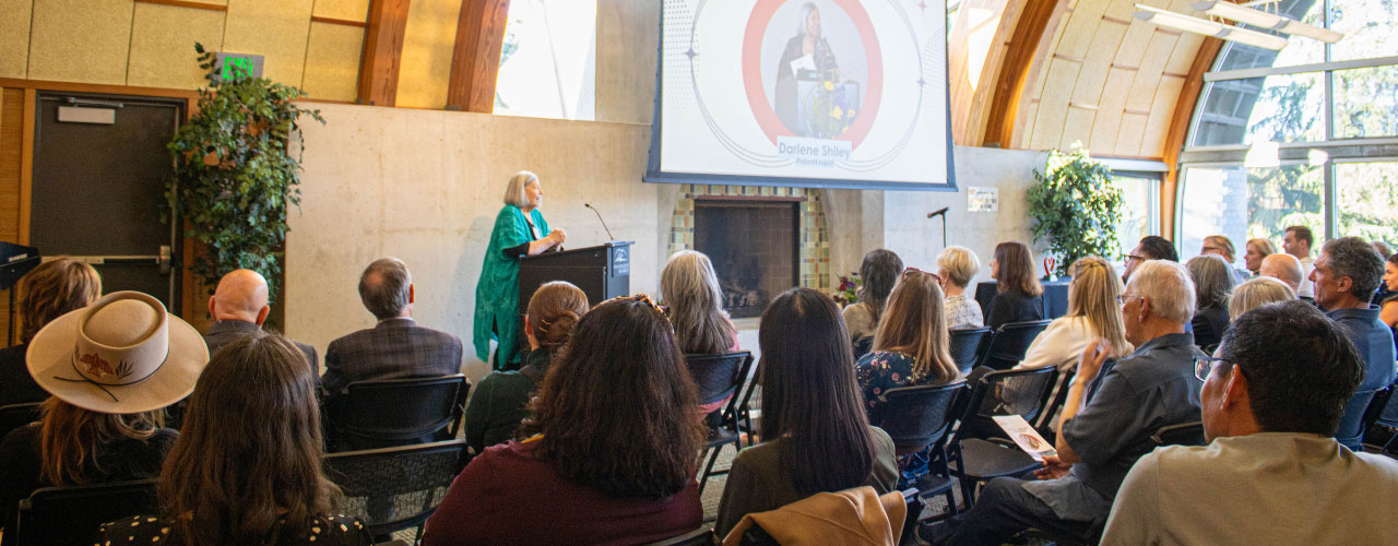 Speaker at podium in front of a large room of participants