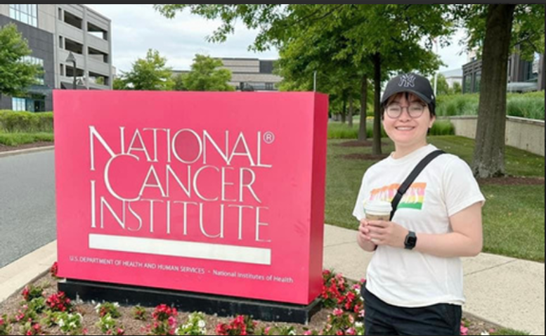 community woman standing in front of sign National Cancer Institute