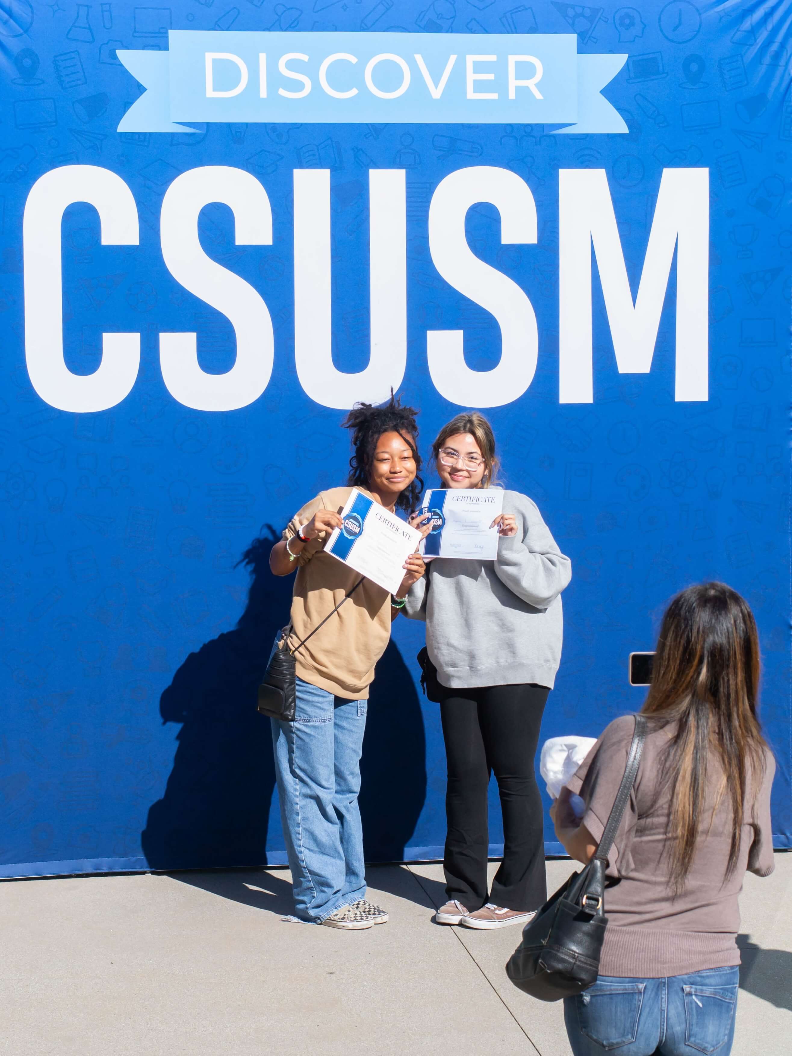 Two students holding up admit on the spot certificates