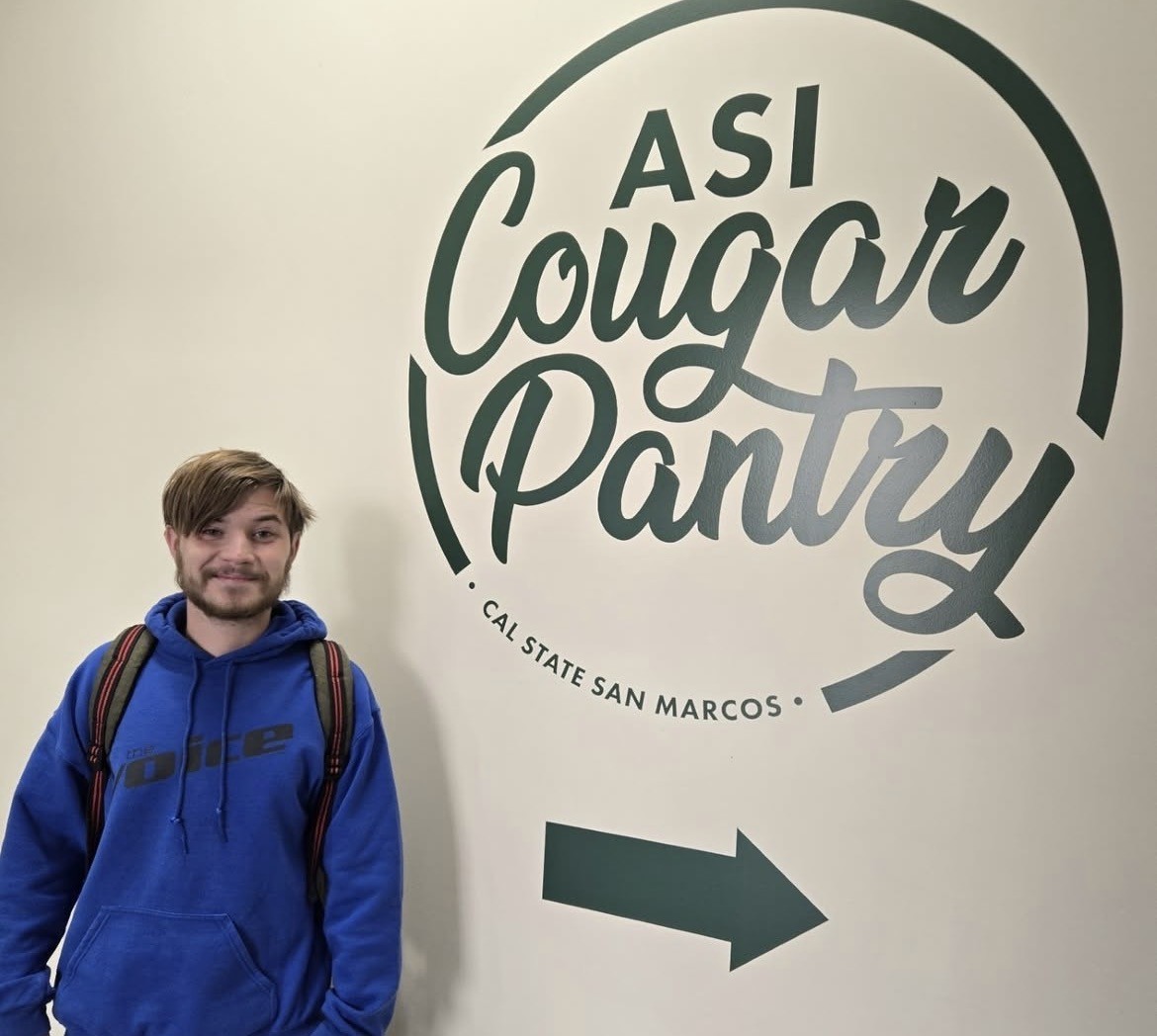 Roman Martens in front of Cougar Pantry Sign