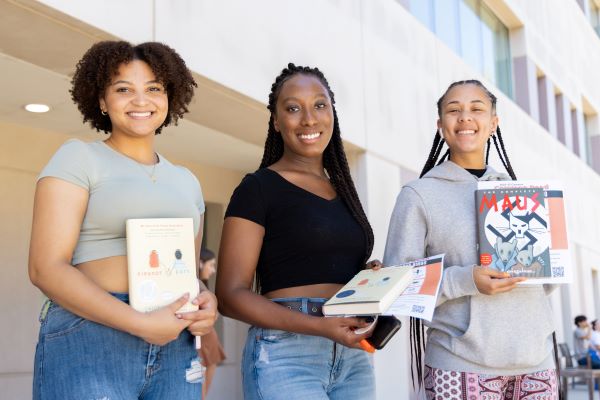 CSUSM Students holding books outside the campus library