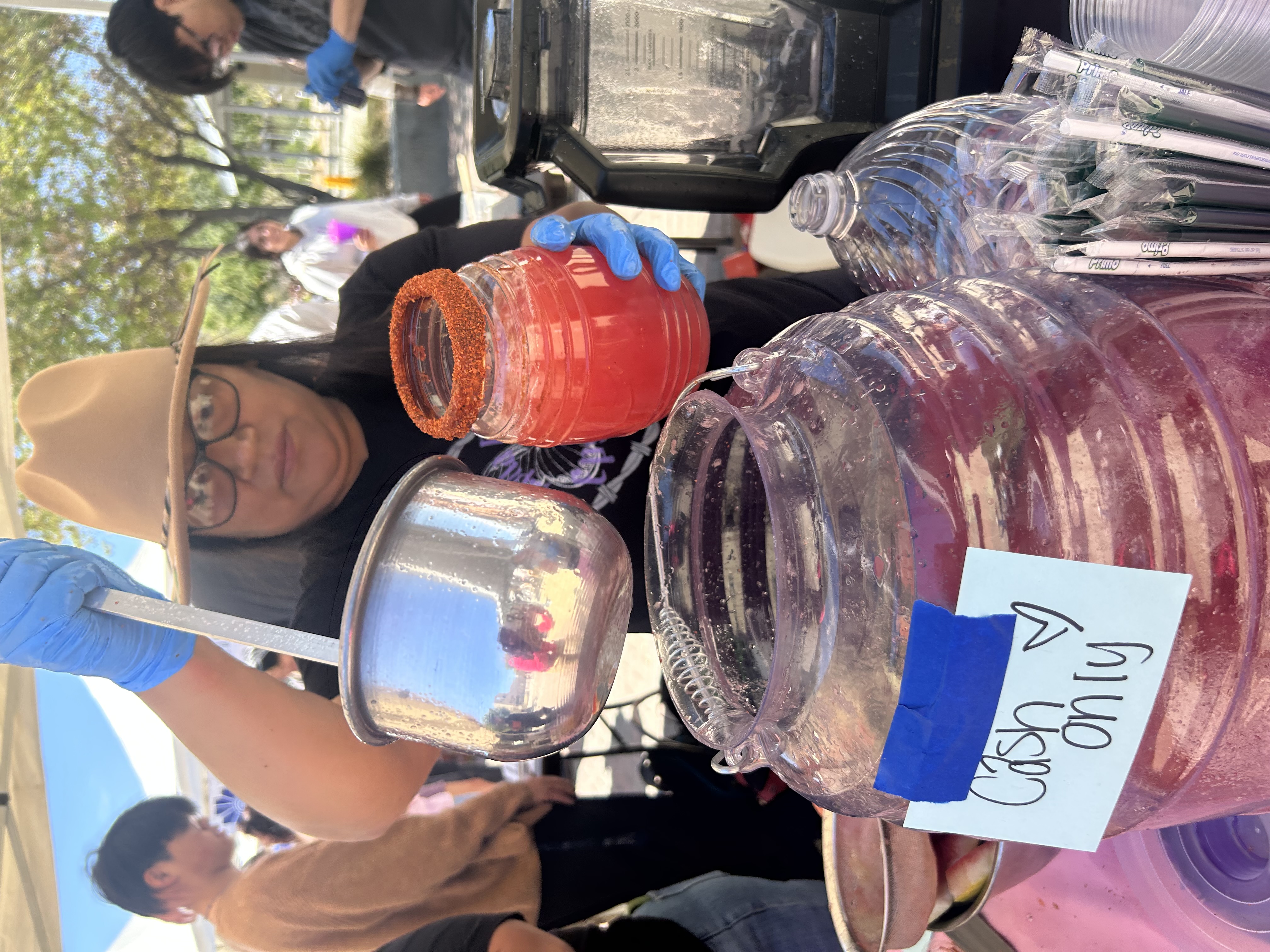 Student ladeling agua fresca into cup at Student Org Market Day.
