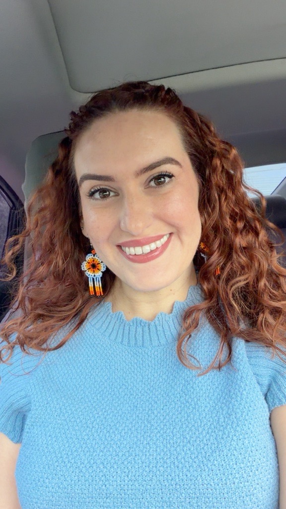 A woman with curly hair wearing a blue shirt.