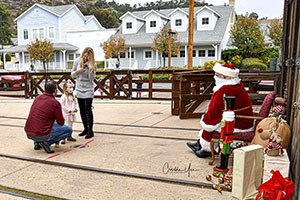 A little girl with her parents six feet away from Santa Claus