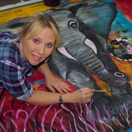 Marilyn Huerta painting a large canvas with an elephant.