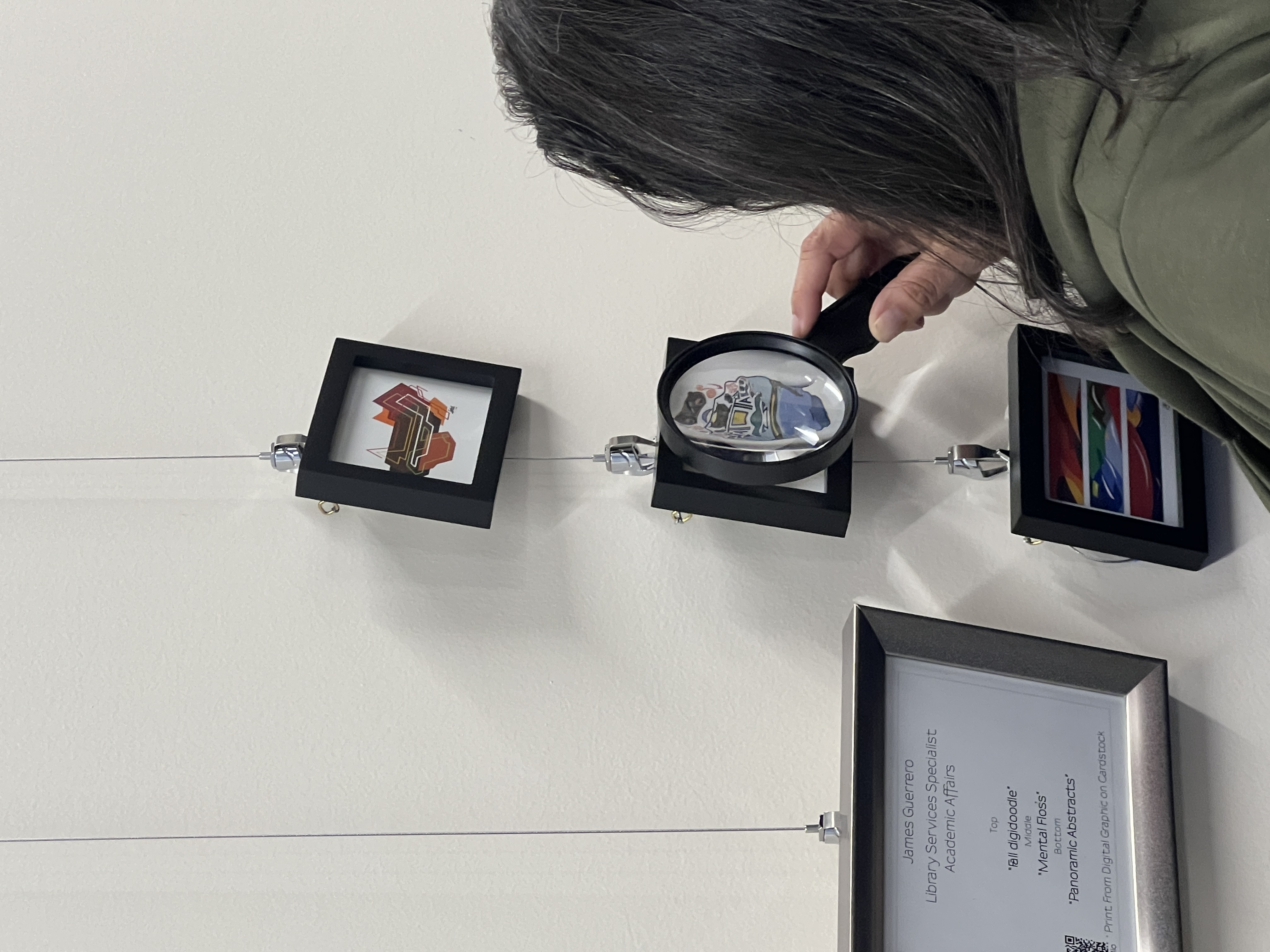 Woman looking through magnifying glass at art.