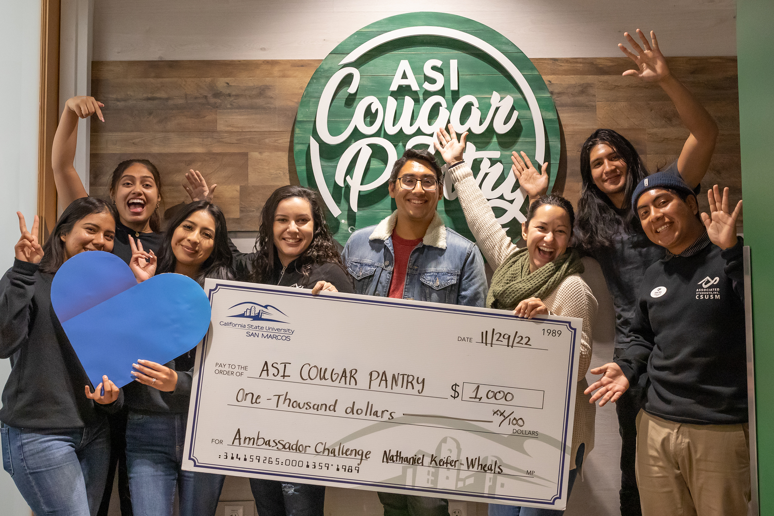 A group of people holding a large check for $1000.