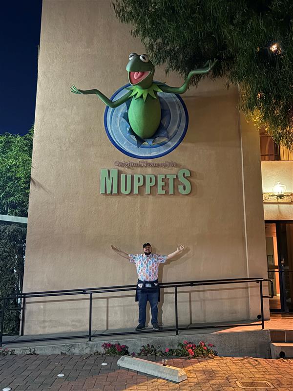Man standing in front of a wall with Kermit the Frog