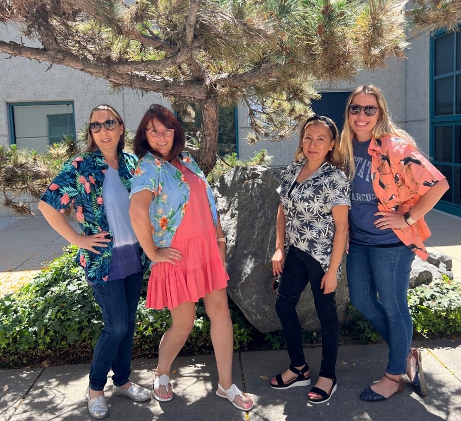 Four smiling people posing in front of a tree
