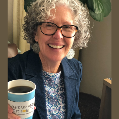 A smiling woman holding up a cup of coffee