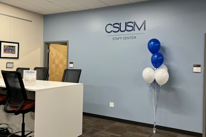 Staff Center logo on a blue wall with balloons.