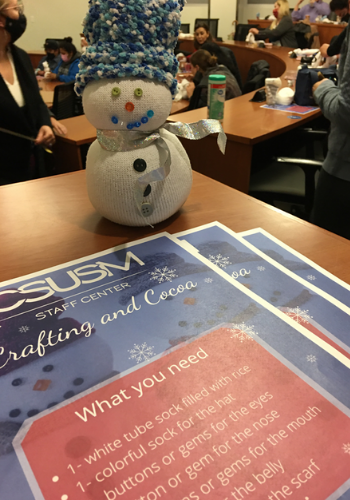 Snowman posed with Crafting and Cocoa event handouts